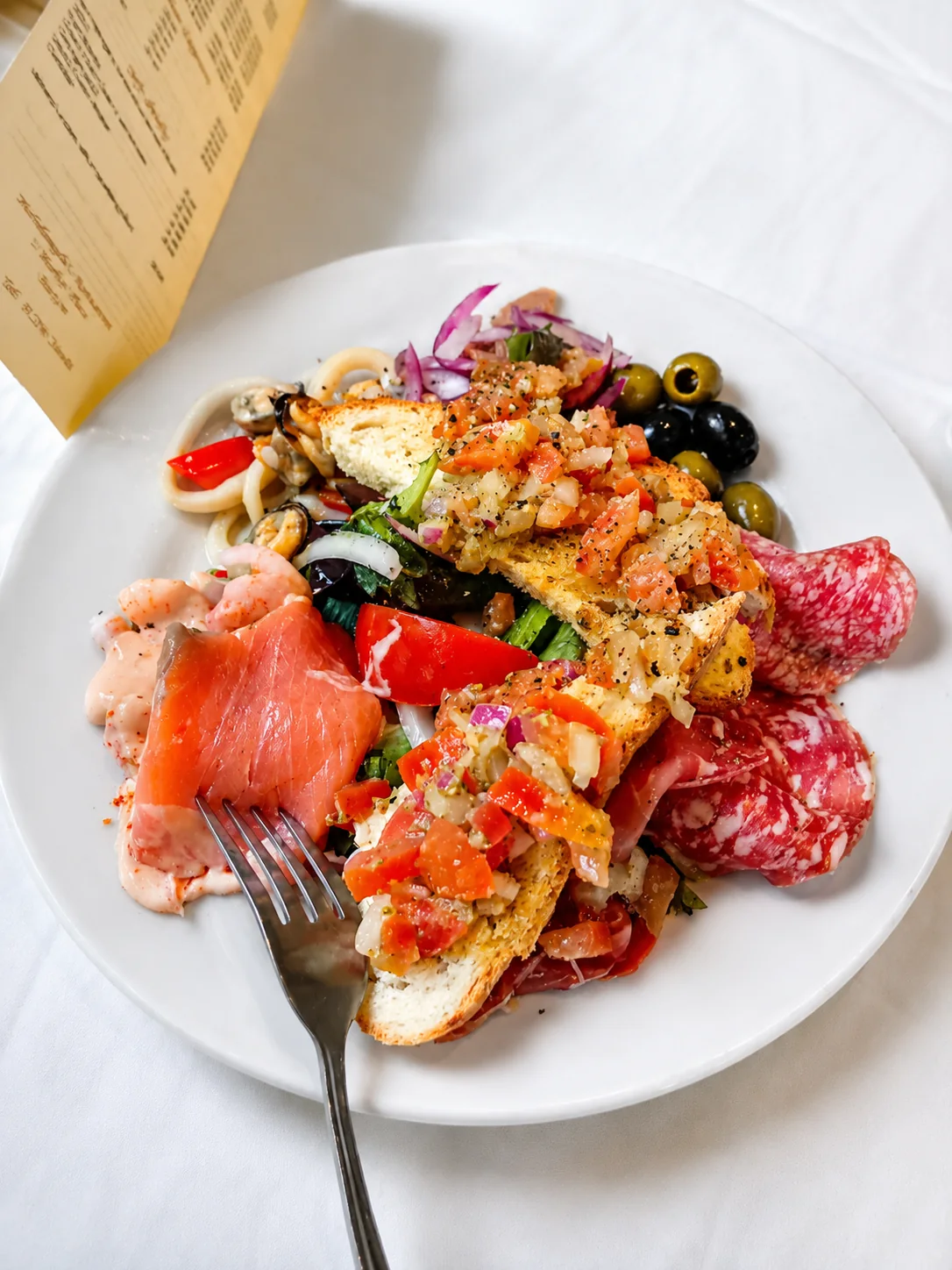 An antipasti platter with cured meats, seafood, olives and bruschetta